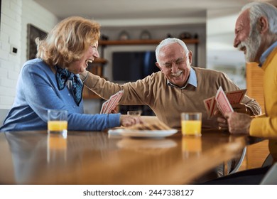 Group of happy seniors having fun while playing cards at home. - Powered by Shutterstock