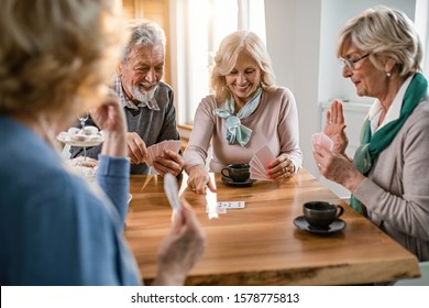 Group of happy seniors playing cards at the table in the living room.  - Powered by Shutterstock