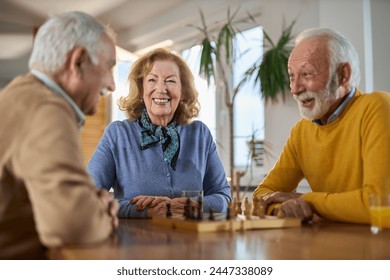 Group of happy seniors talking while playing chess  at home. - Powered by Shutterstock