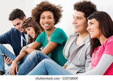 Group Of Happy Smiling Friends Sitting In A Row