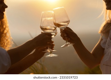 A group of happy smiling girlfriends raise a toast with glasses of white wine on a sunset. Close shot.	 - Powered by Shutterstock