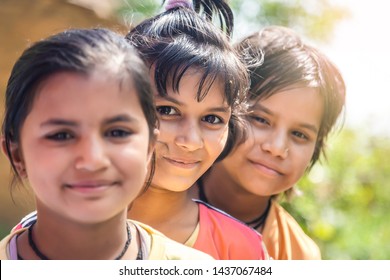 Group Of Happy Smiling Indian Little Village Girls Standing In Front Of Mud House.