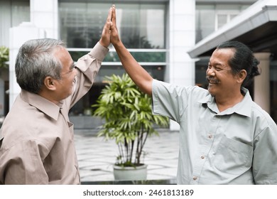 Group of happy smiling old senior friends greeting with high-five gesture, concept of old friends reuniting with long-lasting friendship - Powered by Shutterstock