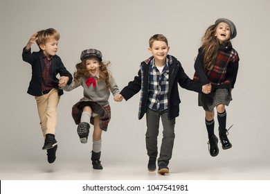 The group of happy smiling teen girls and boys on a pastel studio background. Stylish young teen girls posing at studio. Classic autumn style. Teen and kids fashion concept. children's fasion concept