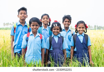 Group Of Happy Smiling Village School Kids In Uniform Standing At Middle Paddy Field By Looking Camera - Concept Of Friendship, Education And Togetherness