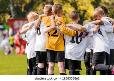 Group of happy sports boys huddling in a team. Happy school kids play sports together. Children motivating each other before playing a soccer football game. Sports Competition for Youth