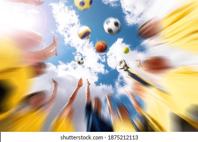 Group of happy sports team with coach throwing team sports balls. Summer sky with clouds in the background. Children playing team sports outdoor; soccer, basketball, volleyball, handball, tennis ball - Powered by Shutterstock