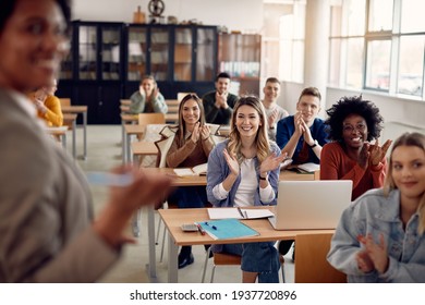 Grupo de estudiantes felices aplaudiendo a su profesor mientras asiste a clase en el aula de la universidad. 