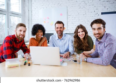 Group Of Happy Students And Teacher Sitting Together In Classroom