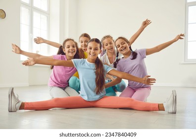 Group happy successful joyful flexible children kid girls in sportswear sit on floor after lesson at sport dance school gymnastic hall recreation club circus studio, spread arms, smile, look at camera - Shutterstock ID 2347840409