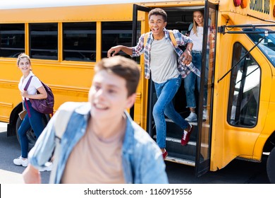 Group Of Happy Teen Scholars Running Out School Bus 