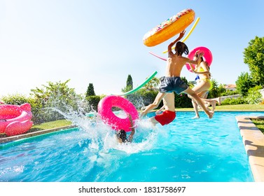 Group of happy teenage kids with inflatable toys jump and splash into water pool jumping together view from side