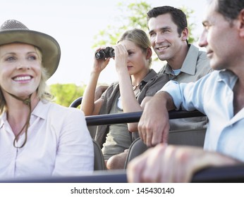 Group Of Happy Tourists On Safari Sitting In Jeep