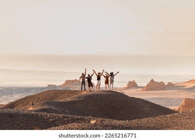 Group of happy tourists stands with open arms at desert view point