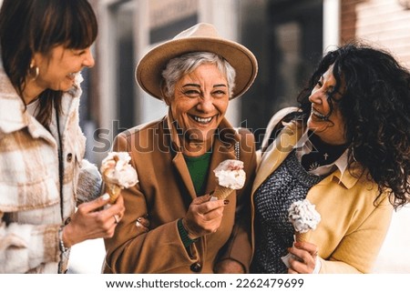 Group of happy women eating ice cream outdoors at city urban street- Three older mature friends girls having fun and walking together outside-Joyful Elderly lifestyle concept