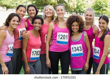 Group of happy women participating in breast cancer marathon standing together park