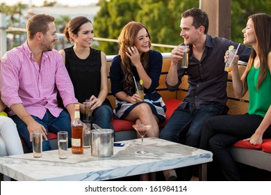 Group Of Happy Young Adults Having Drinks And Talking At A Terrace