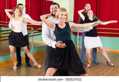 Group Of Happy Young Adults Having Tango Class At Dance Studio. Selective Focus 