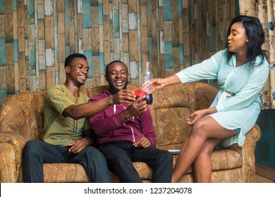 Group Of Happy Young African Friends Hanging Out Together Indoors Sitting Together On A Couch Making A Toast Holding Cups And A Bottle 