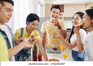 Group Of Happy Young Asian People Enjoying Delicious Pizza At House Party