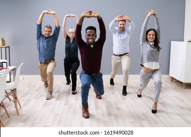 Group Of Happy Young Businesspeople Doing Stretching Exercise In Office