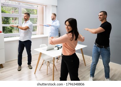 Group Of Happy Young Businesspeople Doing Stretching Exercise In Office