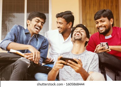 Group Of Happy Young College Students By Looking At Mobile Phone Laughing Loudly At University Campus - Millennials Enjoying Online Video Content Or Social Media By Watching Smart Phone.