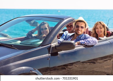 Group of happy young friends in cabriolet with raised hands driving on sunset - Powered by Shutterstock