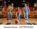 Group of happy young friends having fun and cheering while playing bowling game at the bowling alley
