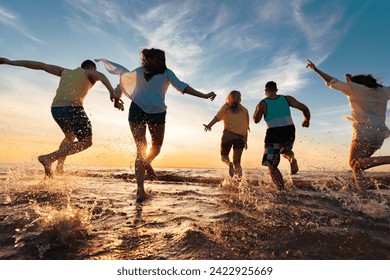 Group of happy young friends are having fun, runs and jumps at sunset beach with lots of splashes - Powered by Shutterstock