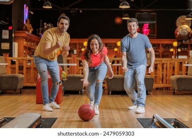 Group of happy young friends having fun and cheering while playing bowling game at the bowling alley