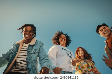 Group of happy young friends having fun outdoors, enjoying sunny day under blue sky. Joyful Gen Z people embracing friendship and laughter. - Powered by Shutterstock