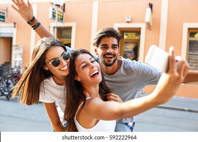 Group of happy young friends having fun on city street.Taking selfie.