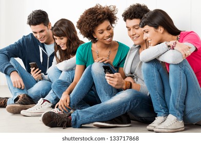 Group Of Happy Young Friends Looking At Cell Phone