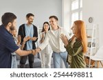 Group of a happy young friends men and women meeting at home standing in circle and shaking hands indoors greeting each other gathering indoors. Friendship, party, people and home leisure concept.