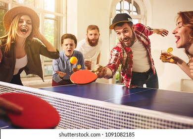 Группа счастливых молодых друзей, играющих в пинг-понг в офисе или в любой комнате. Концепция здорового спорта и настоящих эмоций. Концепции образа жизни, отдыха