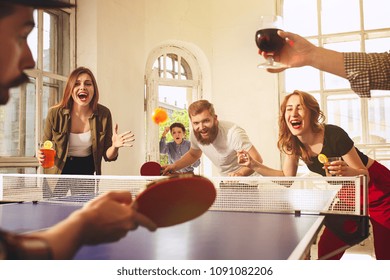 Group of happy young friends playing ping pong table tennis at office or any room. Concept of healthy sport and genuine emotions. Lifestyle, rest concepts
