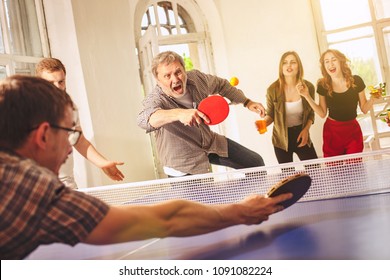 Group of happy young friends playing ping pong table tennis at office or any room. Concept of healthy sport and genuine emotions. Lifestyle, rest concepts - Powered by Shutterstock