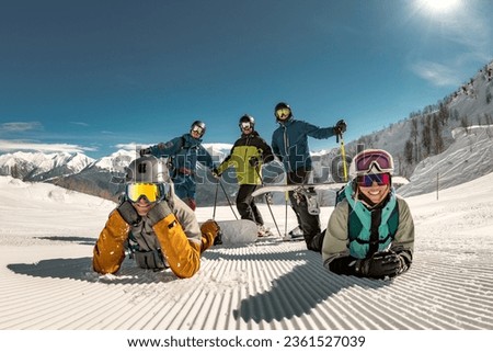 Group of happy young friends skiers and snowboarders are having fun and posing for photo at ski resort. Winter holidays concept
