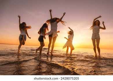 Group of happy young girls are having fun and dancing at sunset sea beach - Powered by Shutterstock