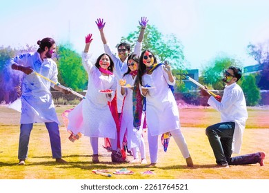 Group of happy young Indian people celebrating holi festival at park outdoor, Playful adult male and friends with colorful paint faces playing with gulal. - Shutterstock ID 2261764521