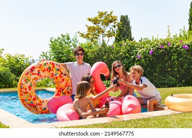 Group Of Happy Young Kids Drink Soda Sitting In The Pool With Inflatables Toys Having Fun