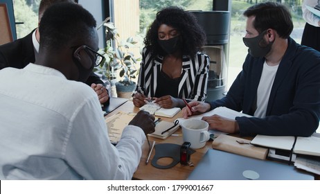 Group of happy young multiethnic business people wearing masks working at office table. Safe workplace after COVID-19. - Powered by Shutterstock