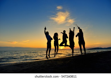 group of happy young people dancing at the beach on beautiful summer sunset - Powered by Shutterstock