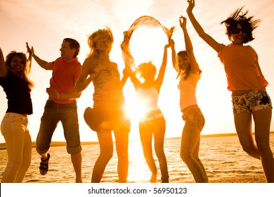 Group Of Happy Young People Dancing At The Beach On  Beautiful Summer Sunset