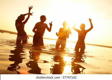 Group Of Happy Young People Dancing At The Beach On  Beautiful Summer Sunset