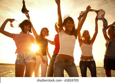 Group Of Happy Young People Dancing At The Beach On  Beautiful Summer Sunset