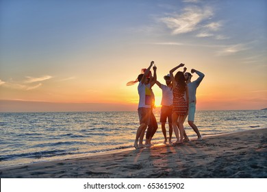 group of happy young people dancing at the beach on beautiful summer sunset - Powered by Shutterstock