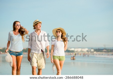 Group of happy young people having a great time on the beach on beautiful summer sunset