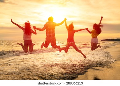 Group Of Happy Young People Jumping On The Beach